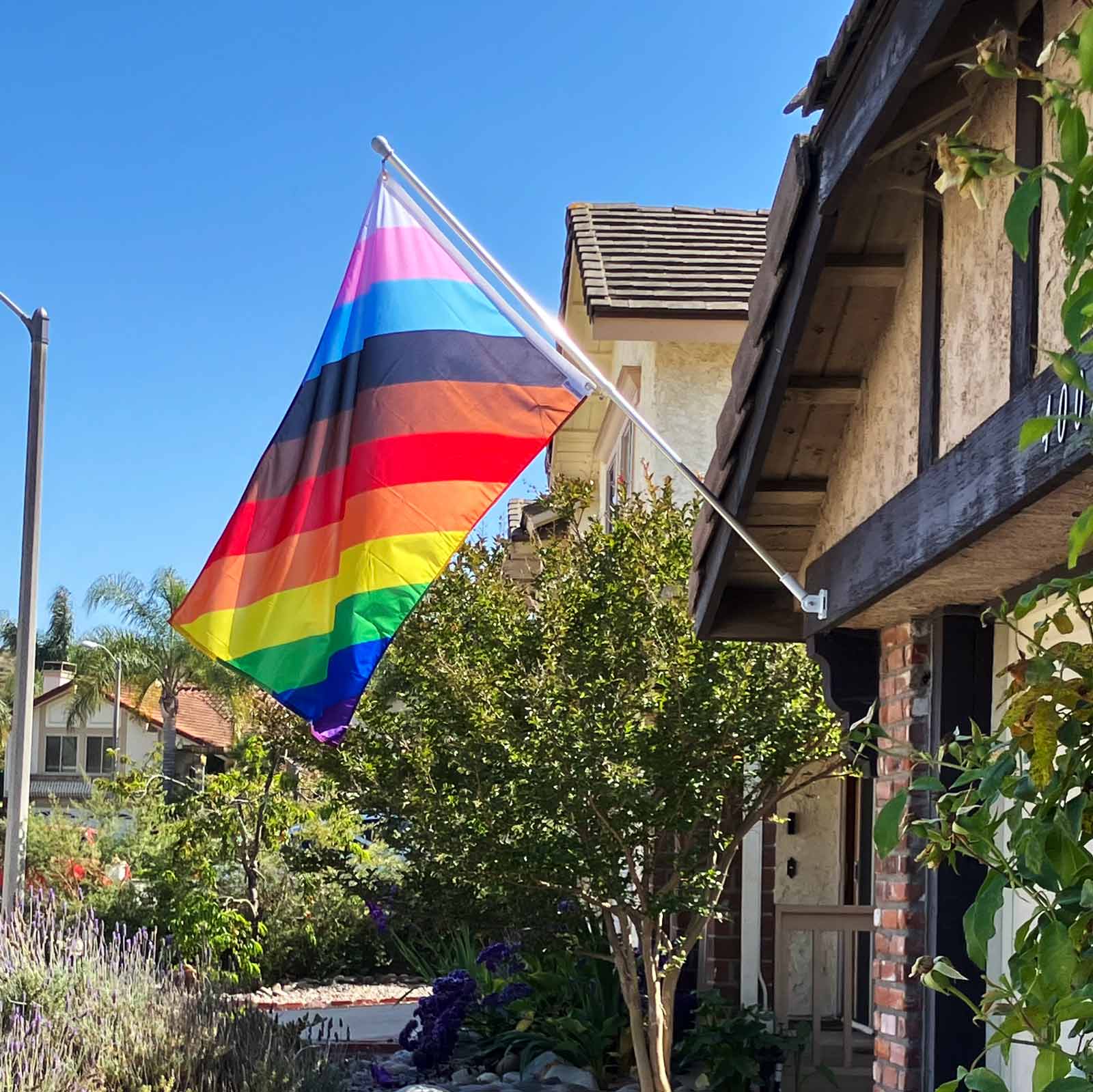 11-Stripe Diagonal Pride Flag hung on a house exterior