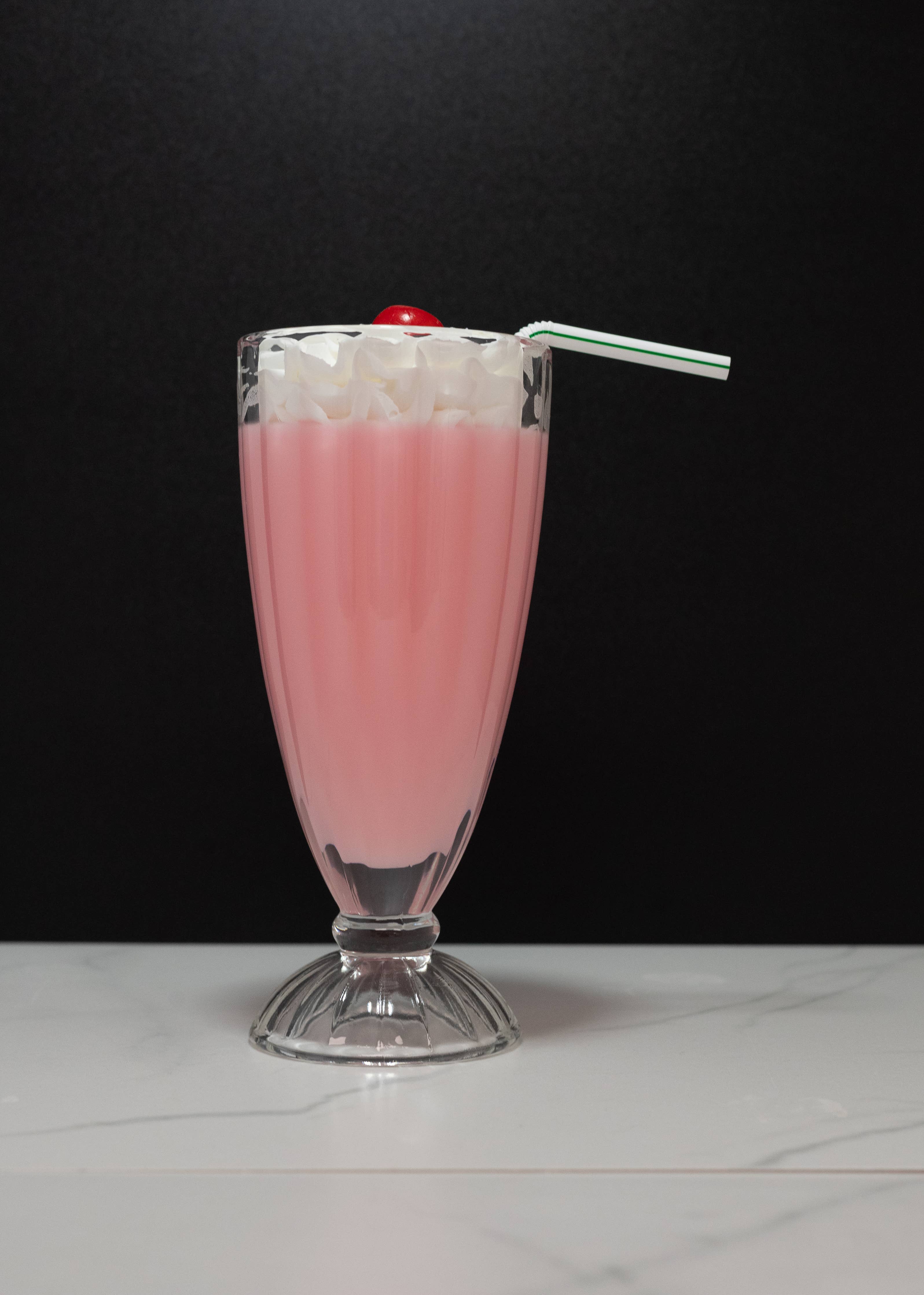 Fake strawberry milkshake — close-up of whipped cream and cherry topper