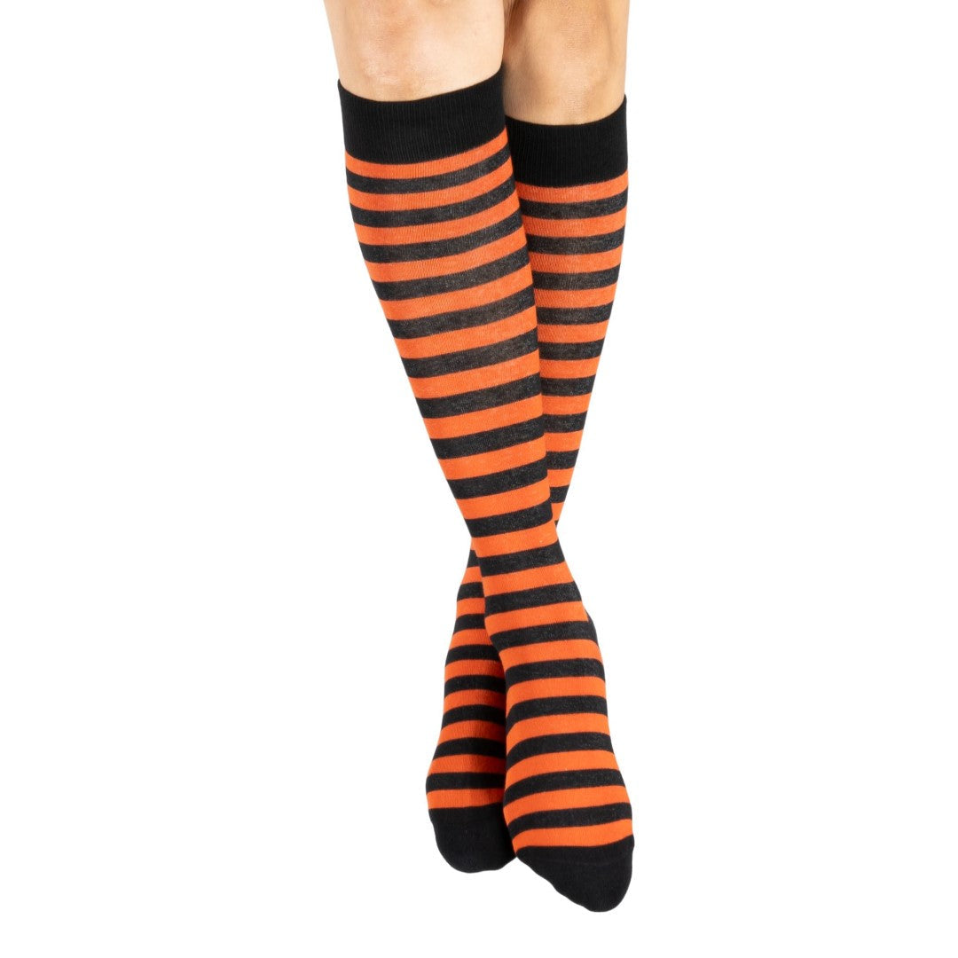 Pumpkin orange and black striped knee high socks — model standing, front view
