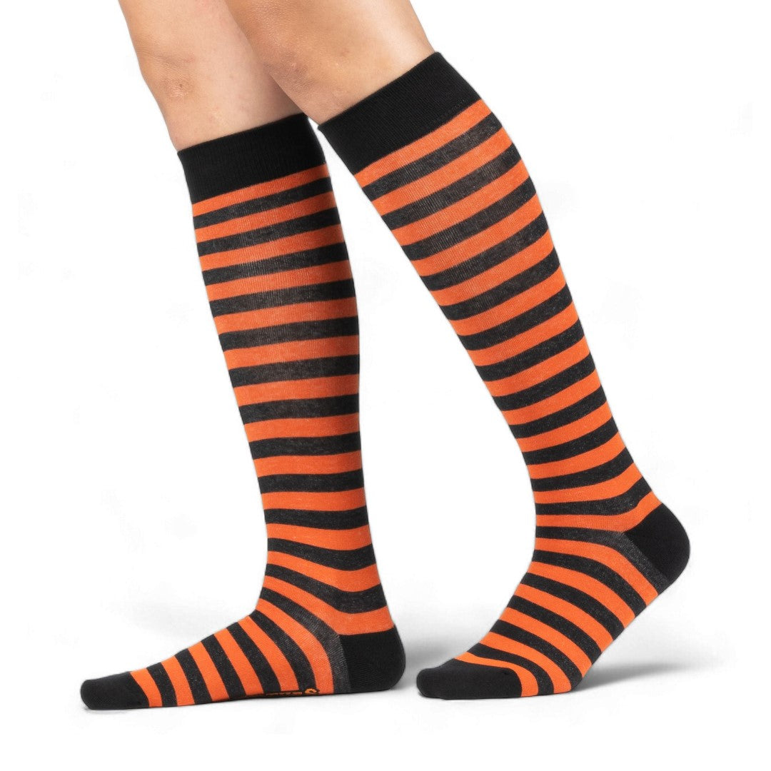 Pumpkin orange and black striped knee high socks — worn on model, full leg view