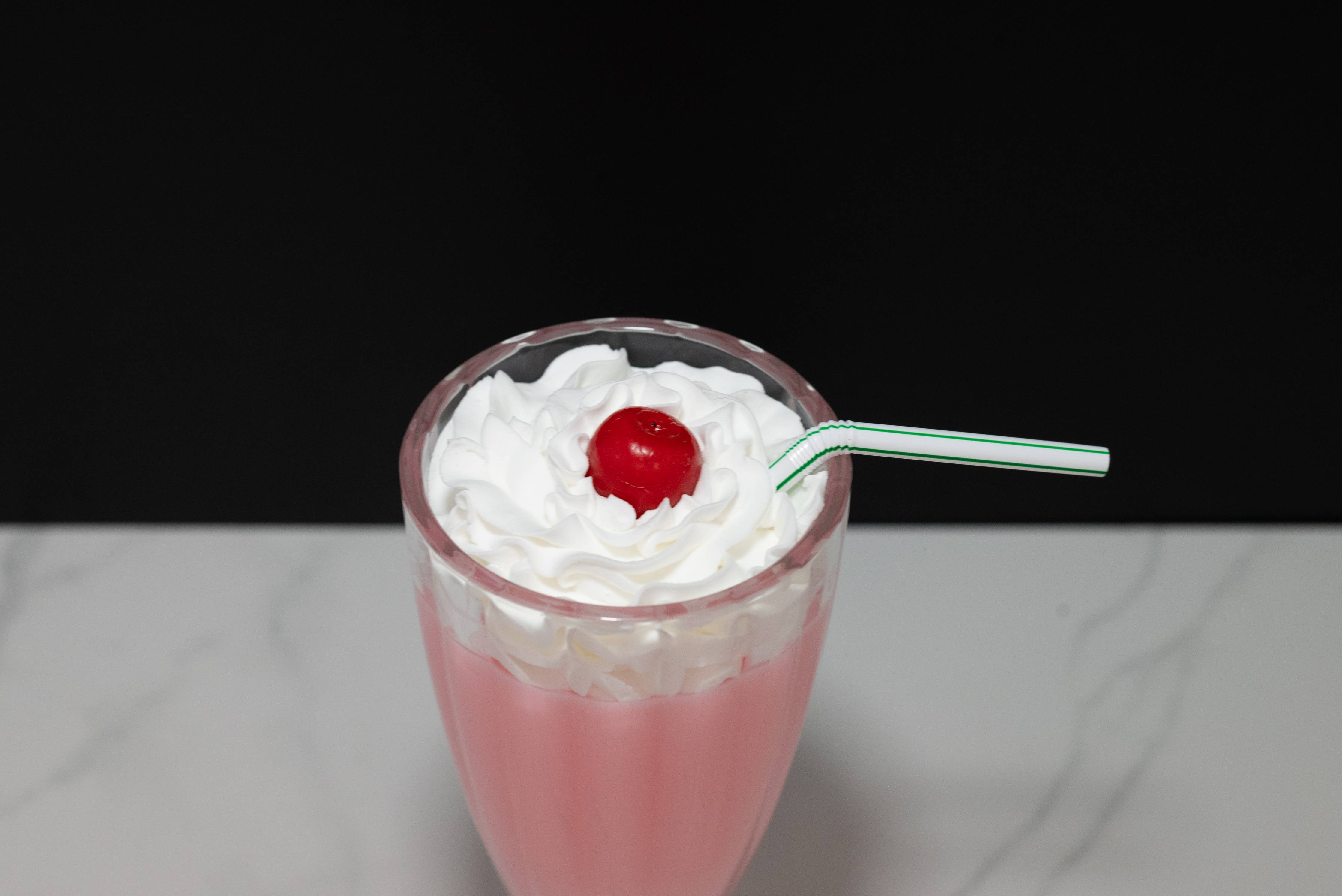 Fake strawberry milkshake — side view showing full diner glass height and pink shake
