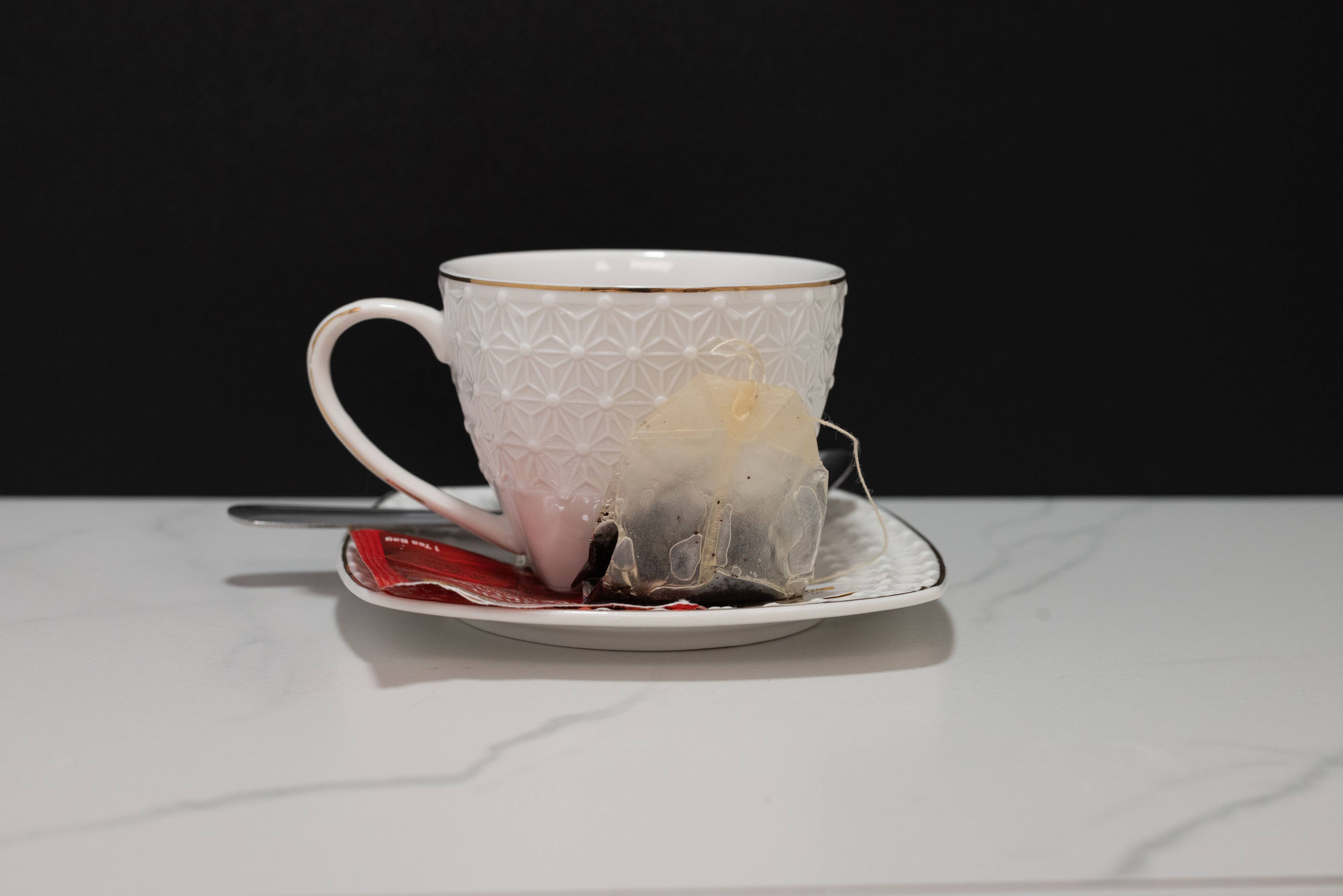 Close-up of fake tea bag and spoon detail on white teacup display