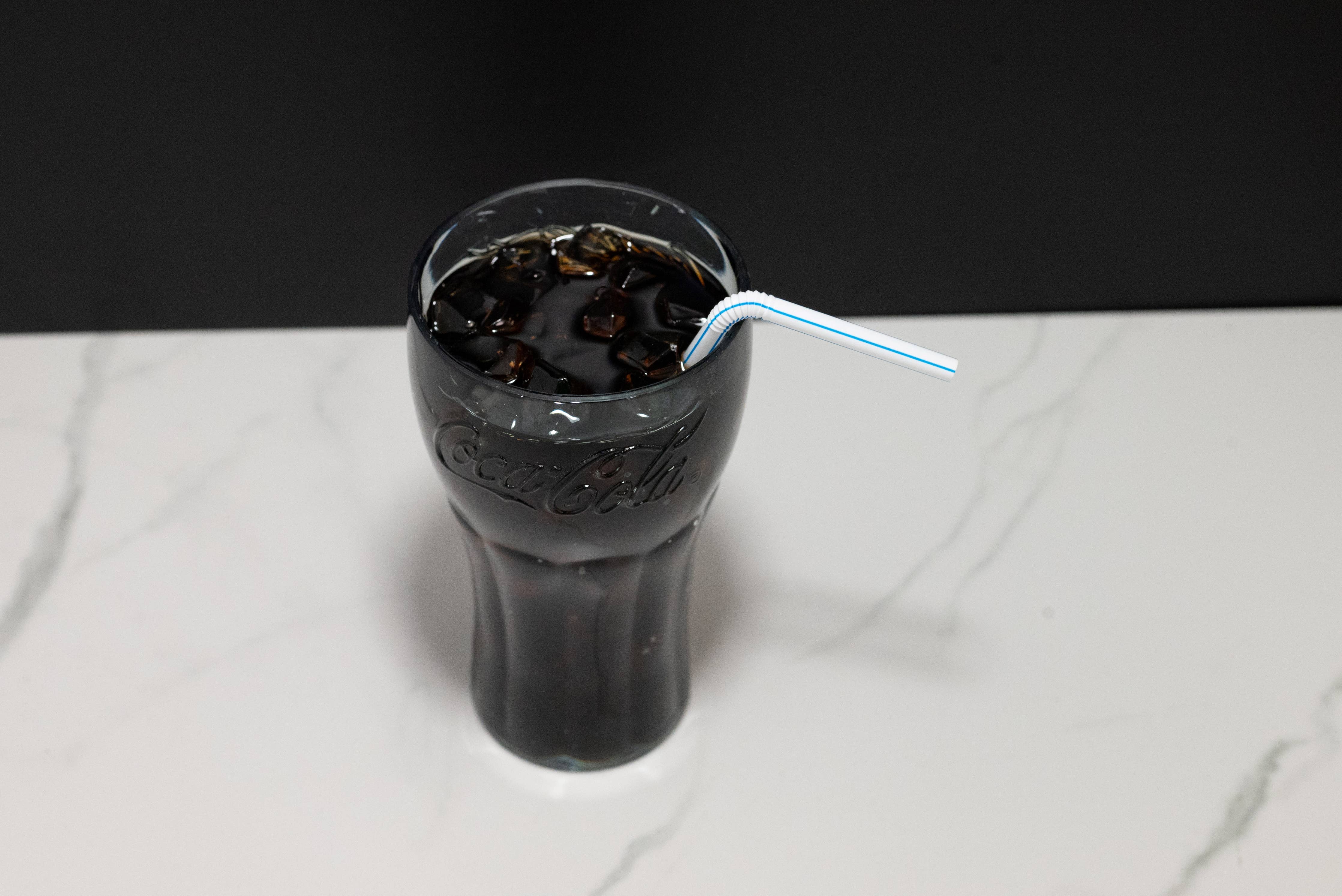 Fake Coca-Cola glass display shown from slight angle highlighting branded glassware and straw