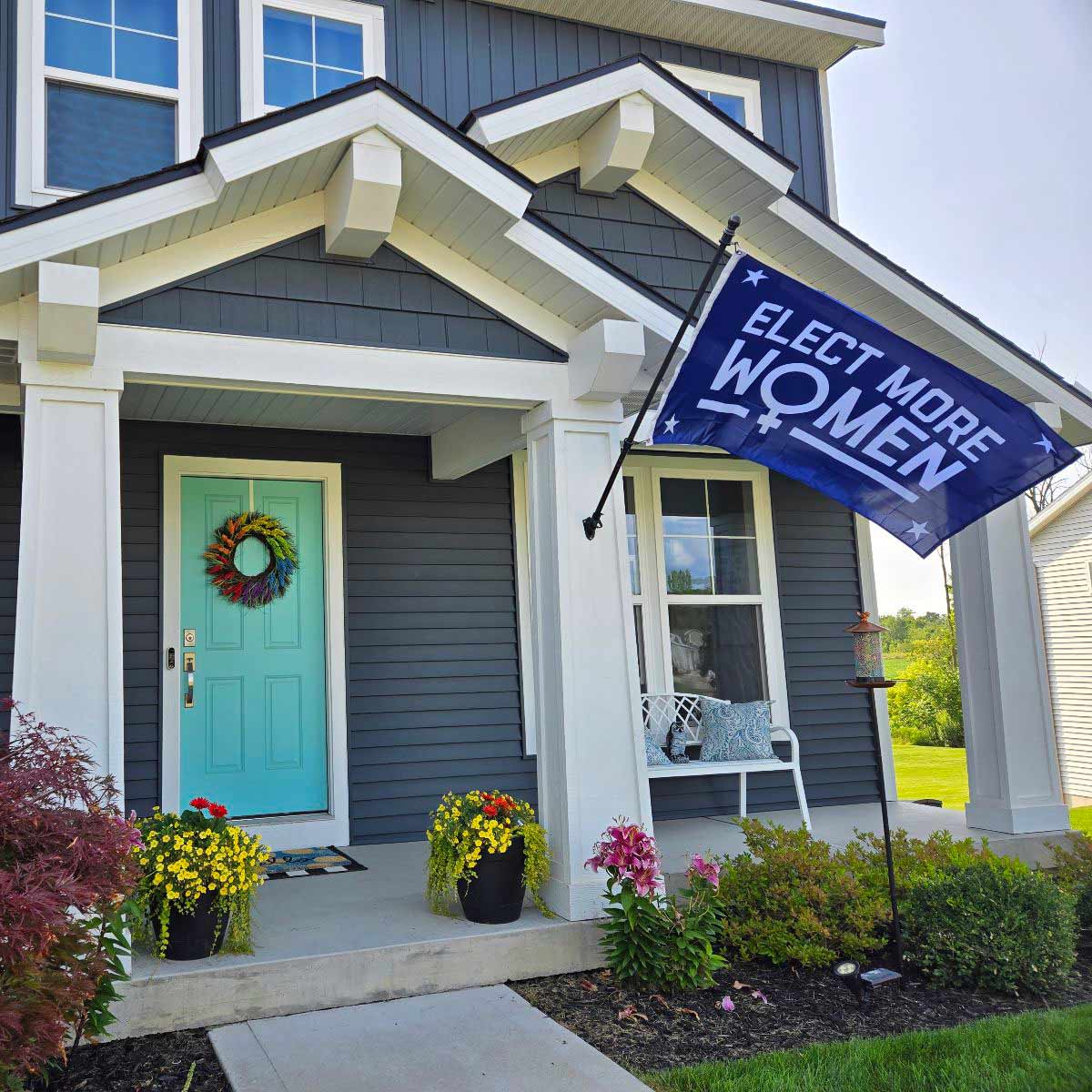 Elect More Women flag displayed outdoors on a house-mounted pole
