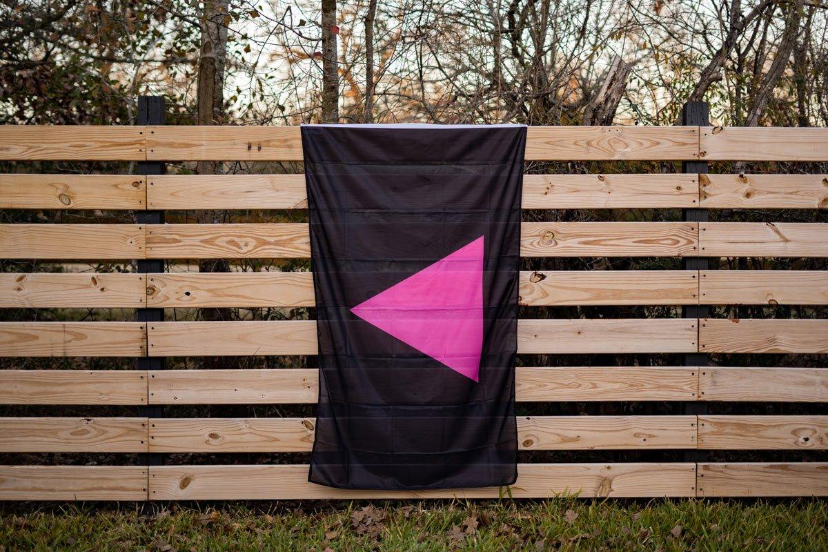 Pink Triangle Pride flag displayed on fence, in-use view