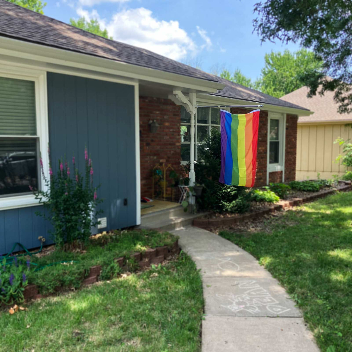 Rainbow Pride flag flying on a flagpole outside a house