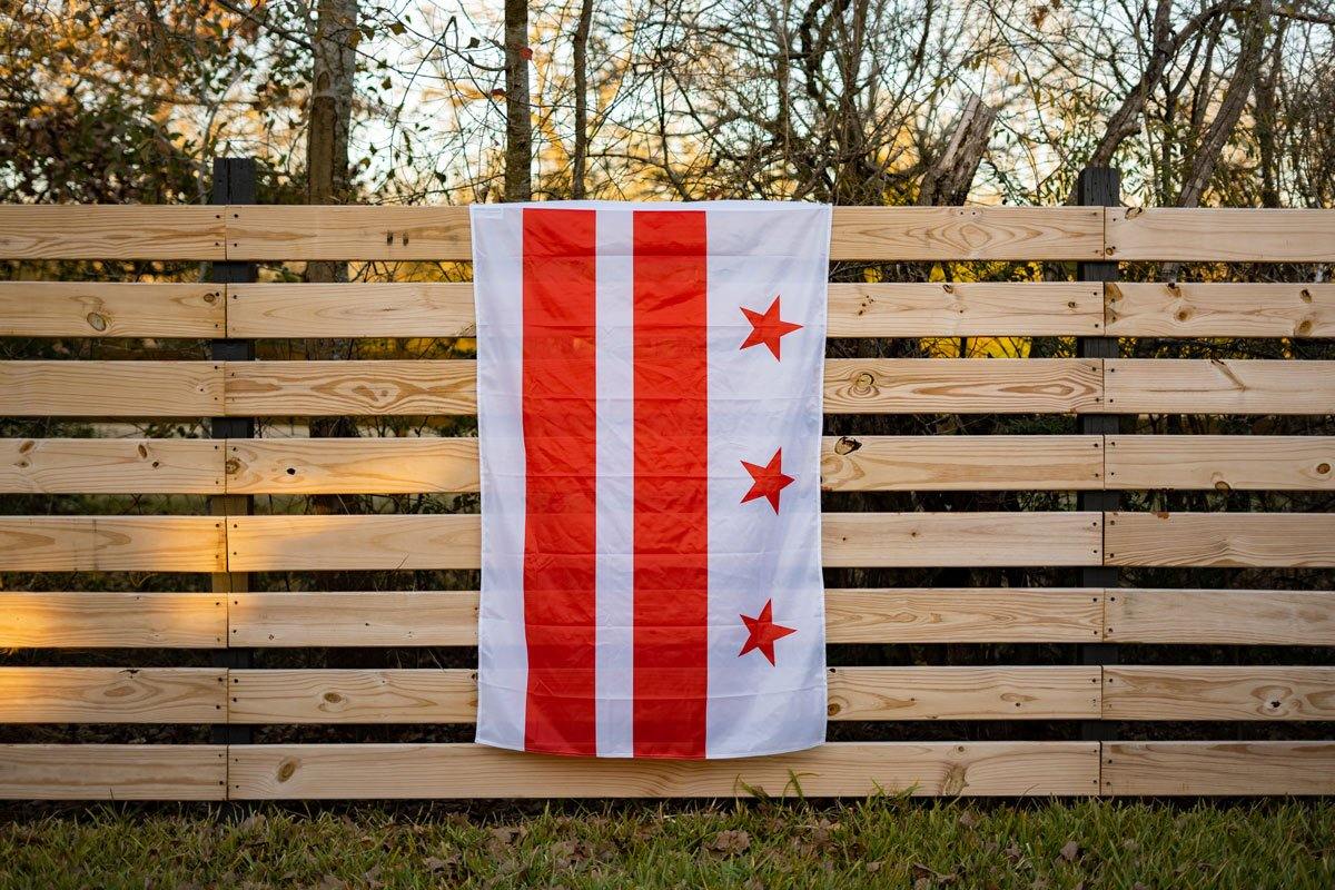 Washington DC flag displayed on a chain-link fence outdoors