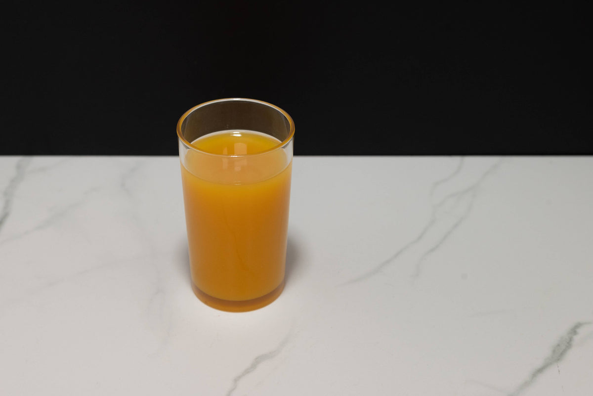 Fake glass of orange juice paired with orange juice carafe for display context