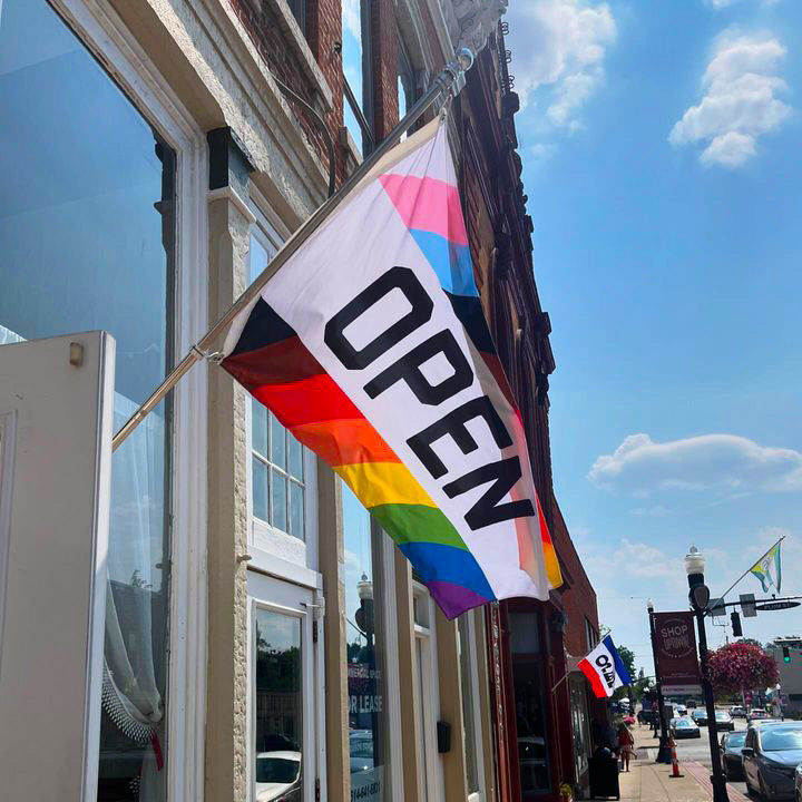 Rainbow LGBTQ+ OPEN flag flying outside a shop storefront